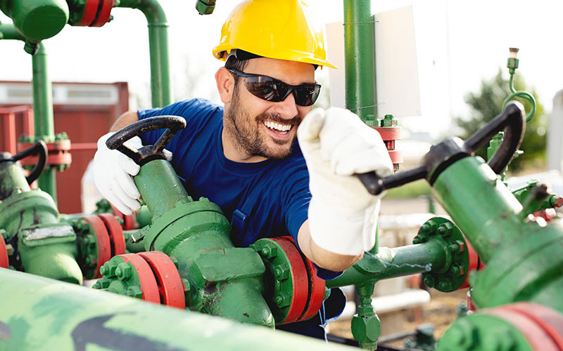 Smiling Man at Work Wearing Safety Glasses, Gloves, and Hard Hat